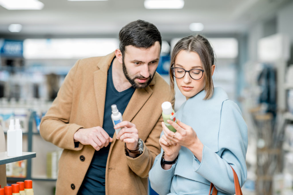 Young couple choosing sunscreen standing pharmacy store