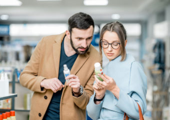 Young couple choosing sunscreen standing pharmacy store