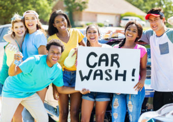 Grupo de jovens segurando um sinal de lavagem de carros scf