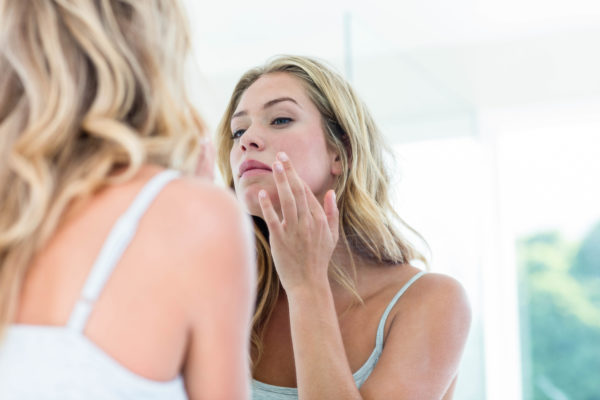 Focused young woman looking at herself in the bathroom mirror