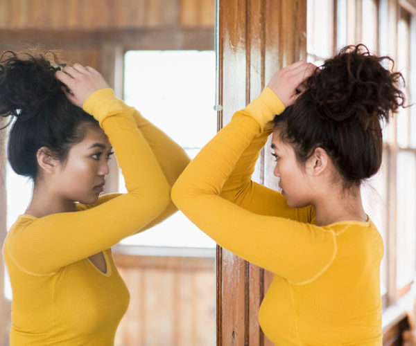 Young woman looking at herself with a tall mirror