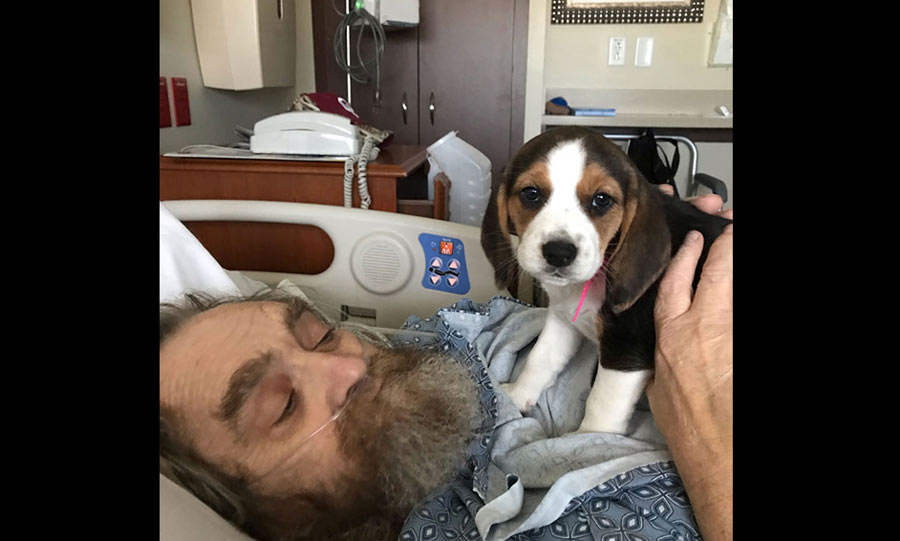 Man holding a cute puppy on a hospital bed