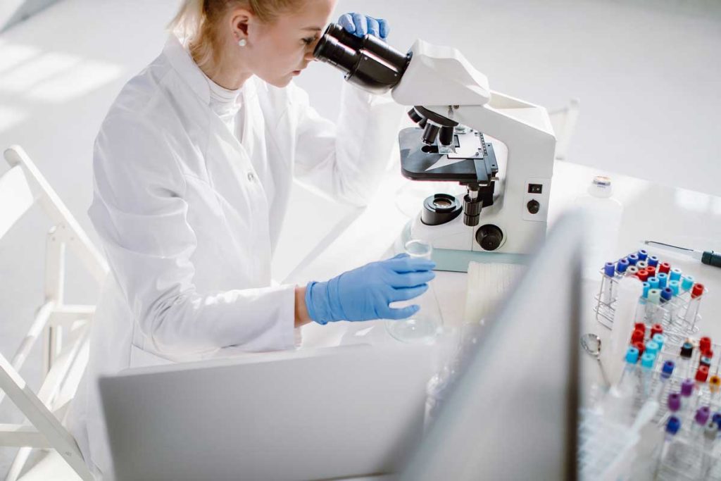 female scientist examining biopsy under microscope
