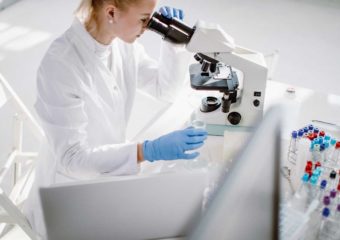 female scientist examining biopsy under microscope