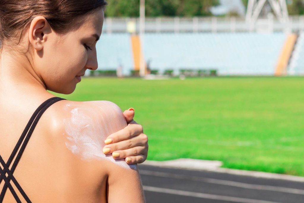 woman applying sunscreen on shoulder