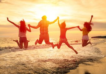 group of happy young people jumping on the beach